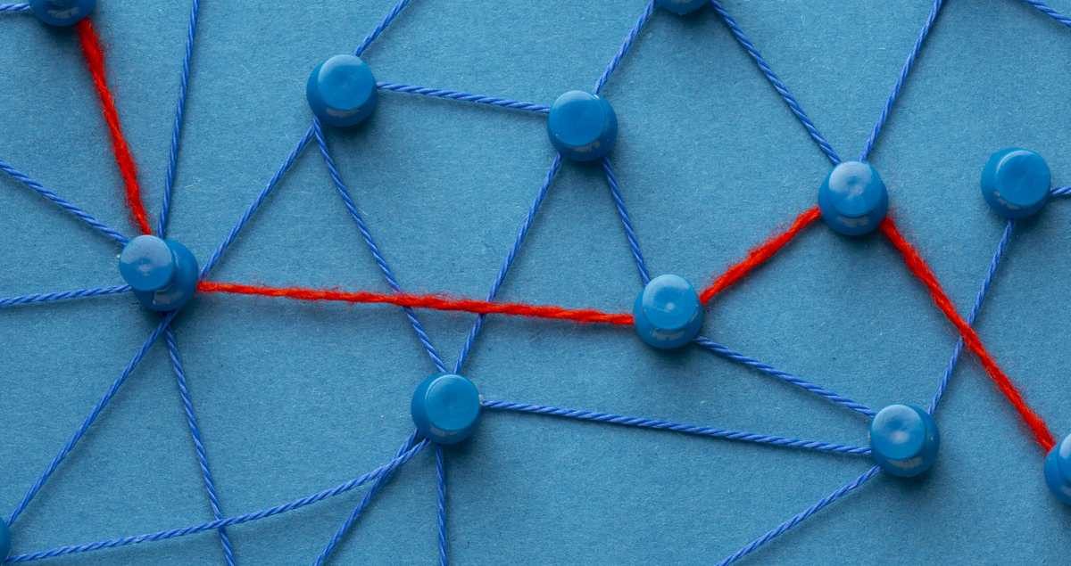 Budget netlinking : des punaises reliées par des fils bleus, dont un fil rouge trace le chemin prioritaire entre quelques nœuds