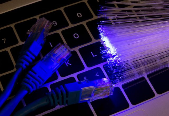 Câbles réseau et fibres optiques lumineuses posés sur un clavier d’ordinateur