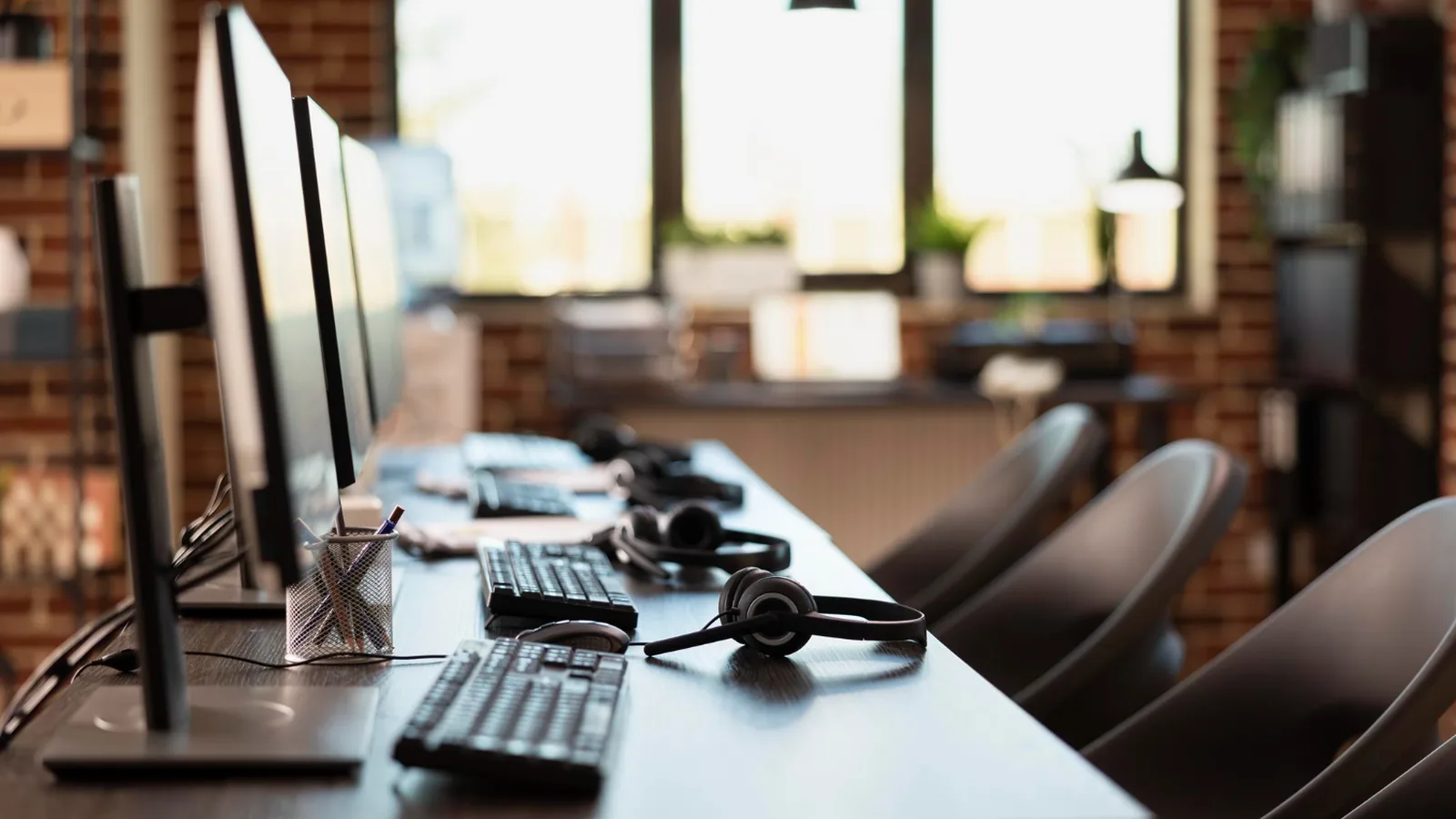 Postes de travail alignés d'un centre de contacts, avec écrans, claviers et casques téléphoniques