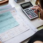 Pièces comptables et bons de paiement vérifiés à la calculatrice, illustration du contrôle fiscal d’une comptabilité externalisée