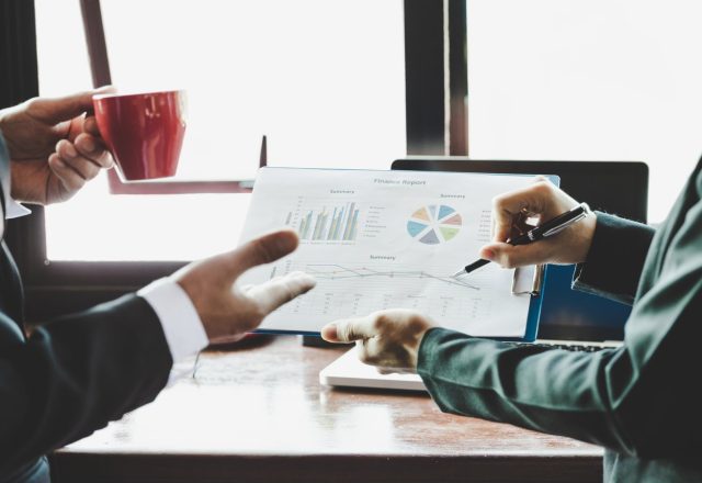 Deux collaborateurs analysant un rapport financier avec graphiques, illustration des données propriétaires publiées