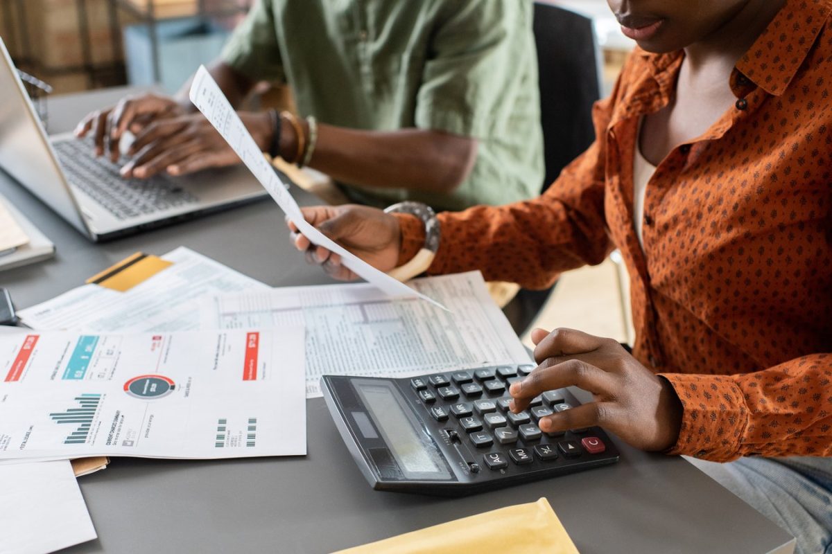 Deux collaborateurs d’une équipe comptable, l’une vérifiant une facture à la calculatrice, l’autre saisissant sur ordinateur portable