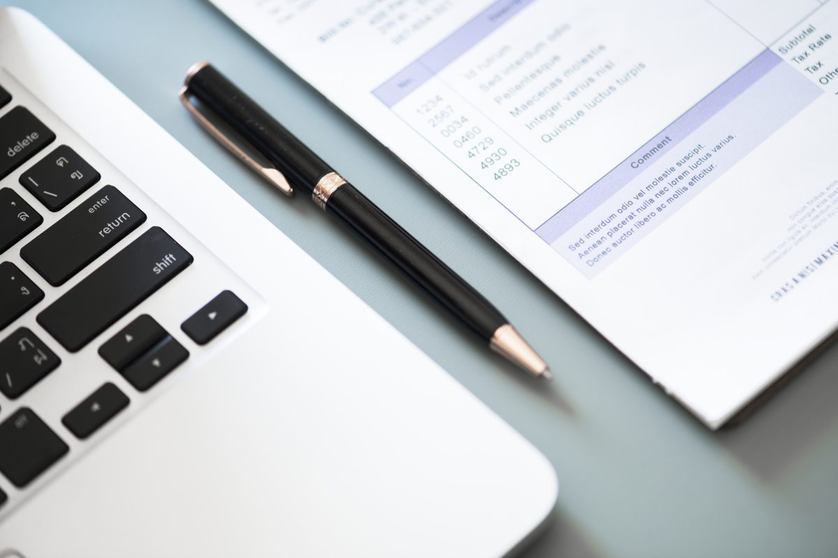 Ordinateur portable, stylo et facture posés sur un bureau
