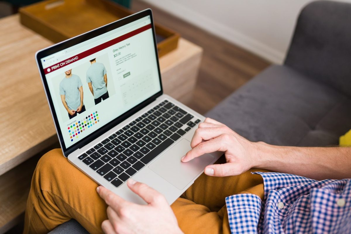 Client consultant sur un ordinateur portable la fiche produit d’un t-shirt, avec photos, prix et nuancier de couleurs