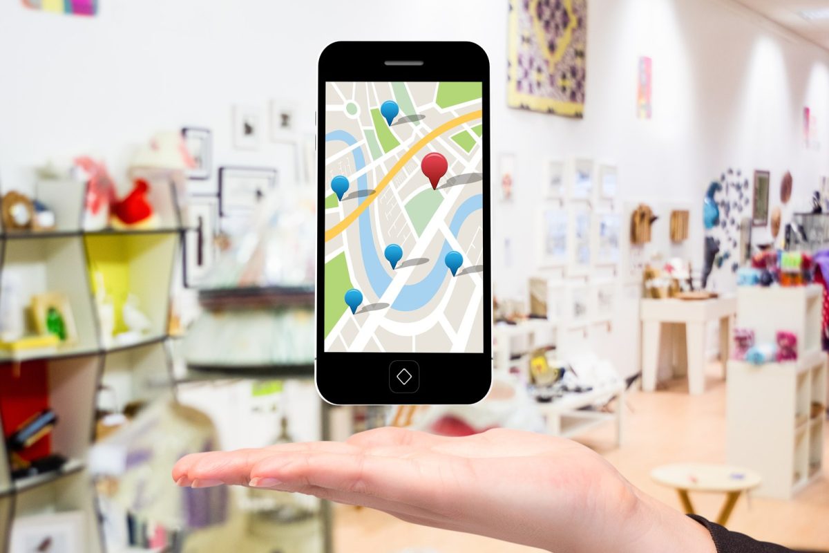 Smartphone affichant une carte avec des repères d'établissements, tenu dans une boutique