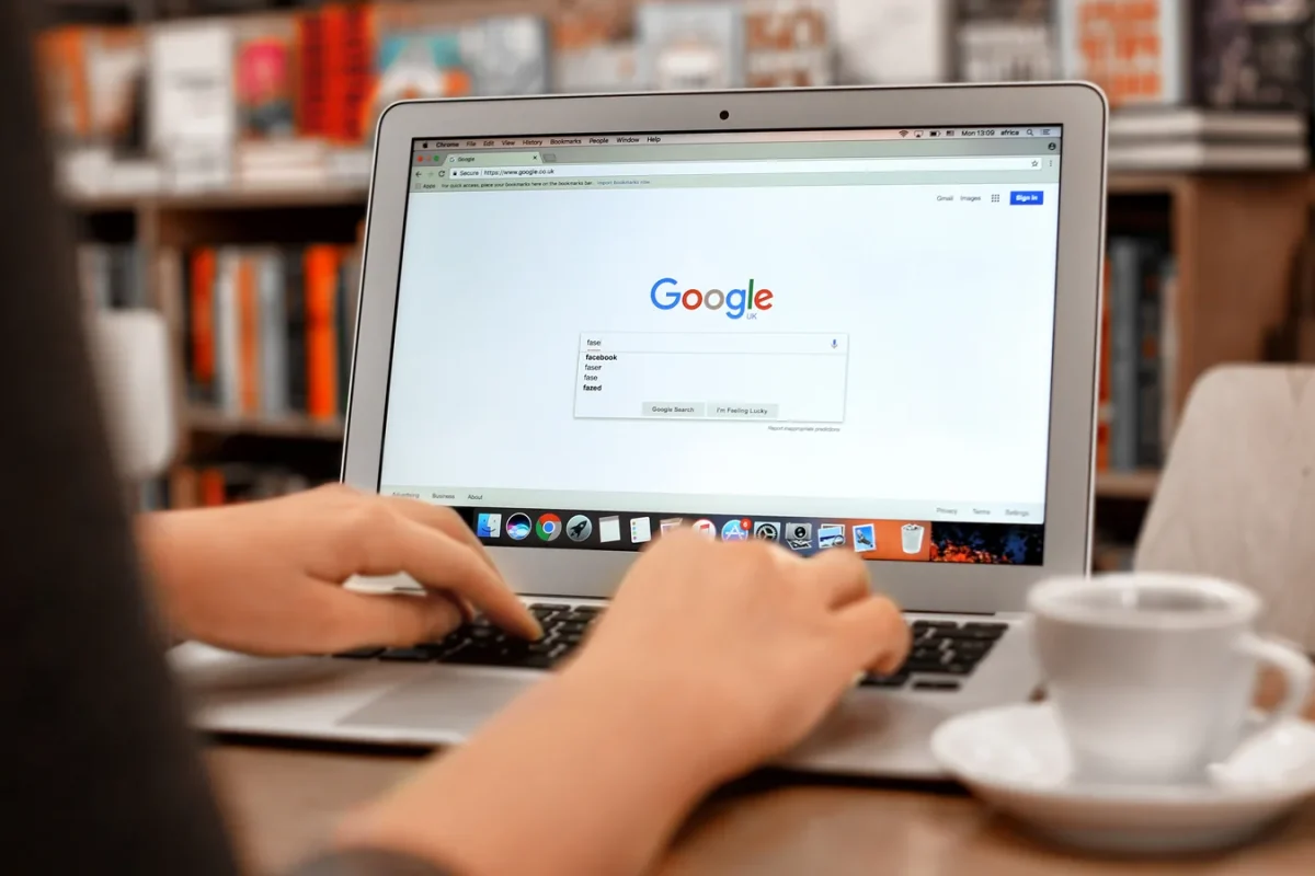 Personne tapant une requête sur un ordinateur portable affichant la page d’accueil de Google
