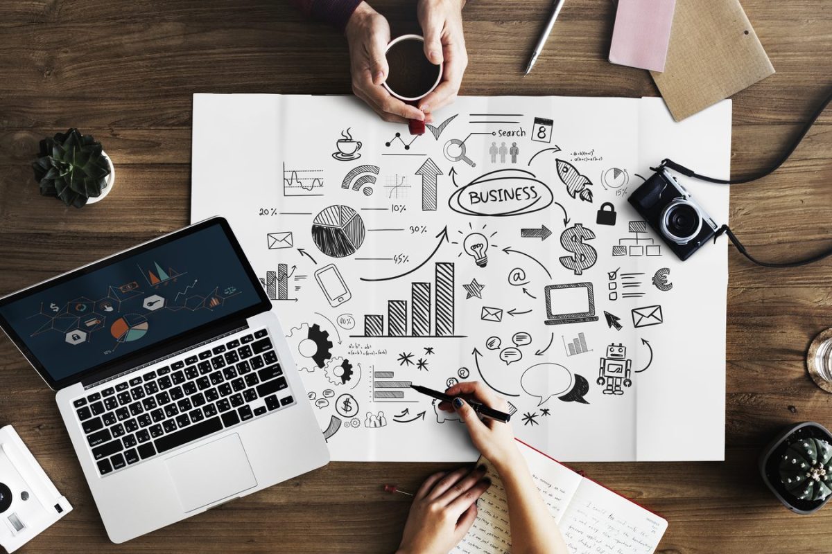 Équipe marketing autour d’un schéma de stratégie de contenu, entre ordinateur portable, graphiques et appareils photo