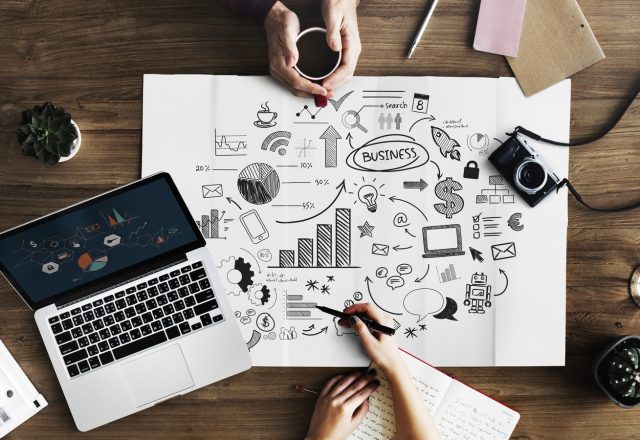 Équipe marketing autour d’un schéma de stratégie de contenu, entre ordinateur portable, graphiques et appareils photo