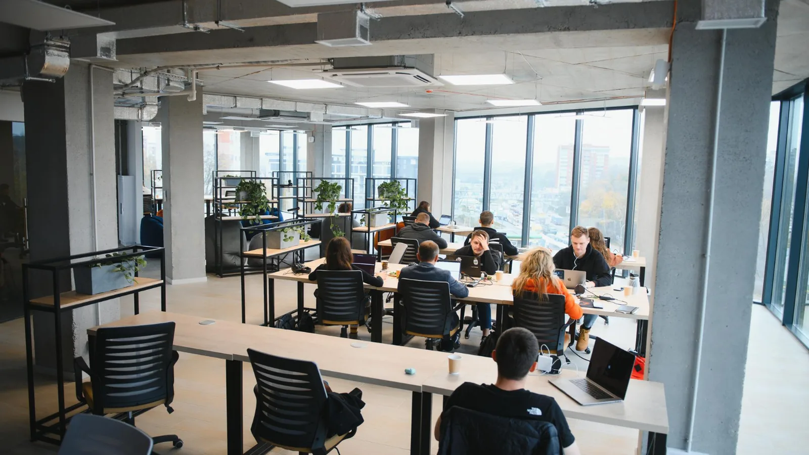 Équipe d'un prestataire au travail sur un plateau de bureaux partagés, illustration des modèles offshore, nearshore et onshore