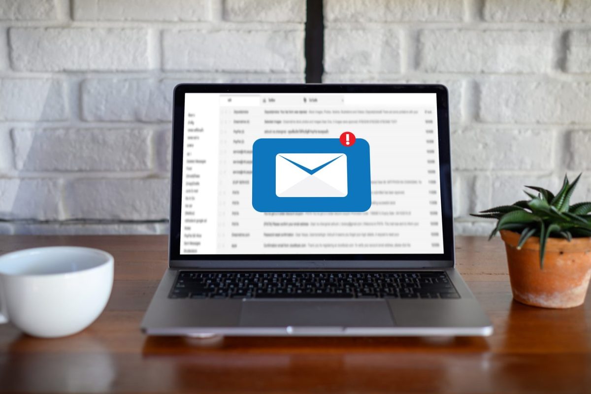 Ordinateur portable affichant une boîte de réception et une icône d’email avec notification, posé sur un bureau