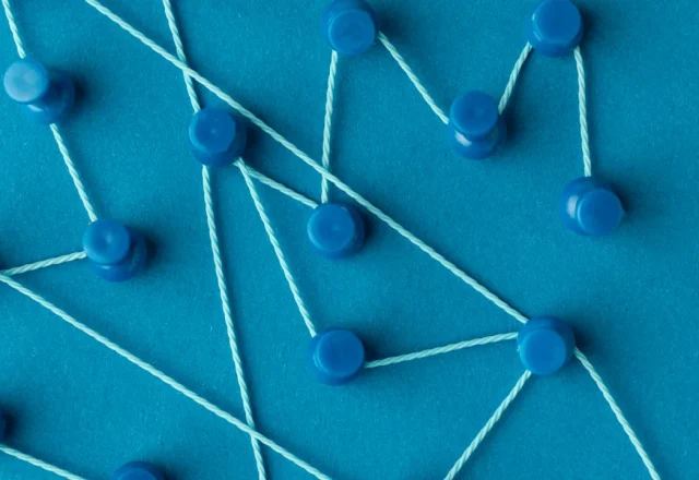 Punaises bleues reliées par des fils sur fond bleu, image d’un réseau de liens