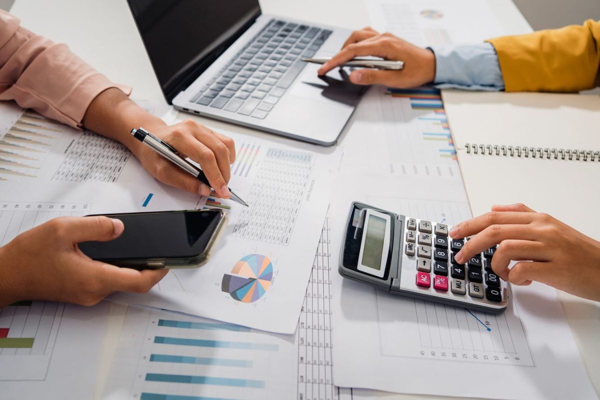 Deux collaborateurs vérifiant des états comptables avec une calculatrice et un ordinateur portable