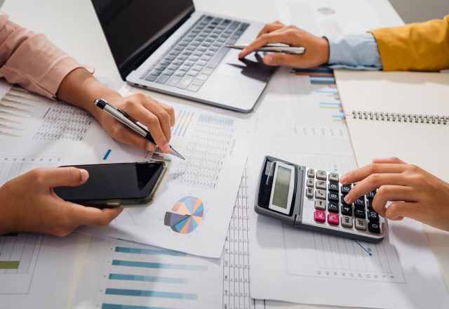 Deux collaborateurs vérifiant des états comptables avec une calculatrice et un ordinateur portable