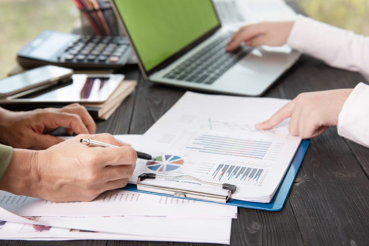 Deux personnes annotent des graphiques et un rapport chiffré devant un ordinateur portable, illustration du chiffrage d’un cas d’usage de l’IA en comptabilité