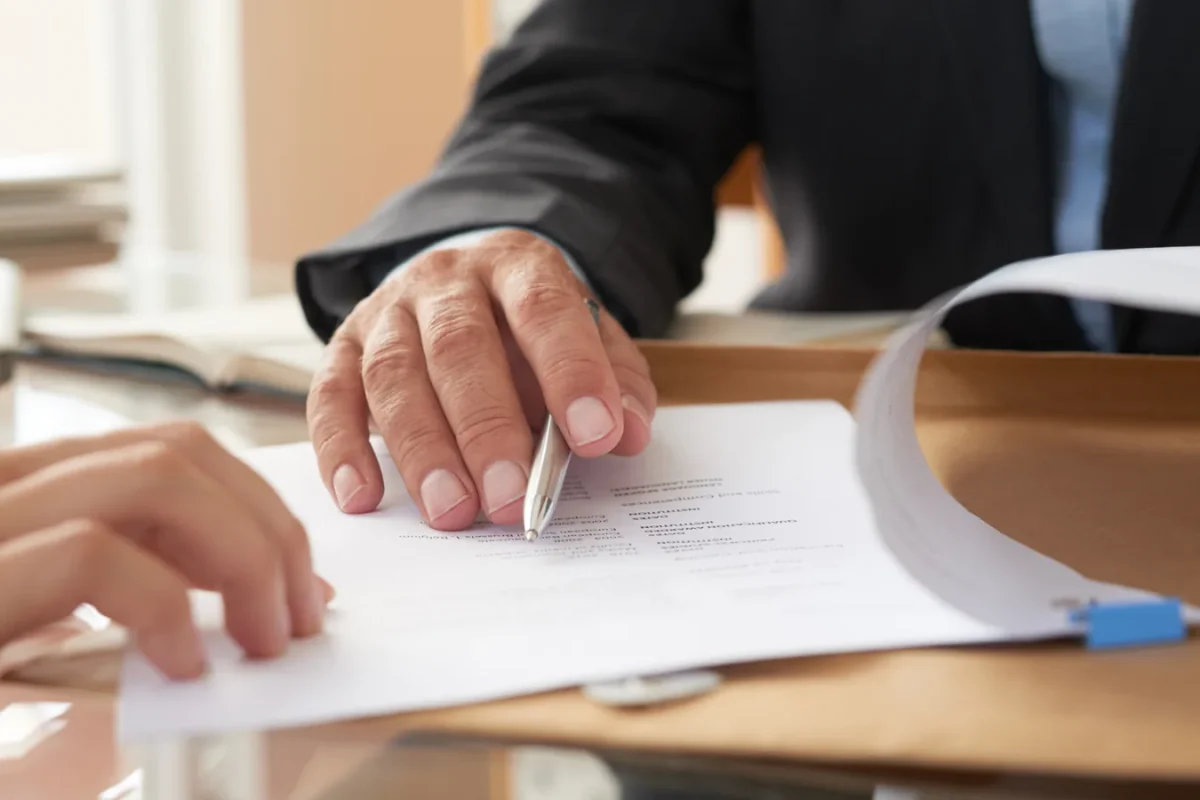 Deux personnes examinent un document imprimé posé sur un bureau, l’une tenant un stylo au-dessus de la page