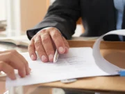 Deux personnes examinent un document imprimé posé sur un bureau, l’une tenant un stylo au-dessus de la page
