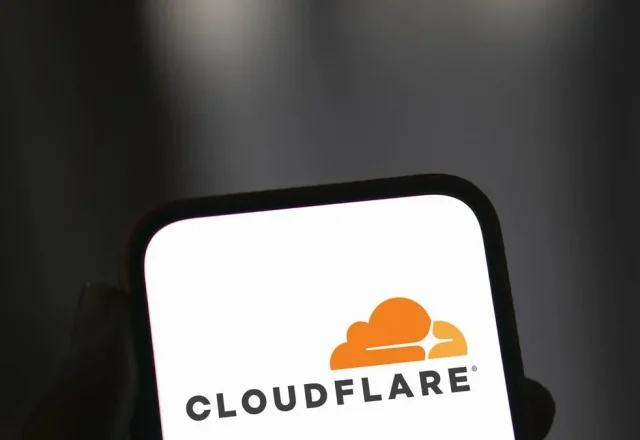 Smartphone affichant le logo Cloudflare tenu en main sur fond sombre