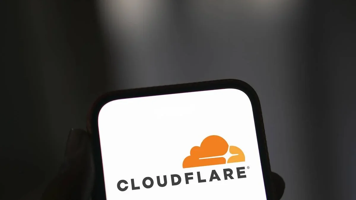 Smartphone affichant le logo Cloudflare tenu en main sur fond sombre