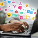 Mains tapant sur le clavier d’un ordinateur portable d’où s’échappent des icônes de réseaux sociaux