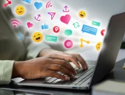 Mains tapant sur le clavier d’un ordinateur portable d’où s’échappent des icônes de réseaux sociaux