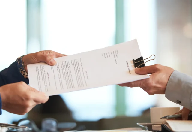 Deux mains se passant un contrat de partenariat imprimé au-dessus d'une table de réunion