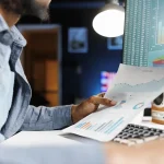 Contrôleur de gestion externalisé analysant les graphiques d’un reporting financier devant son écran