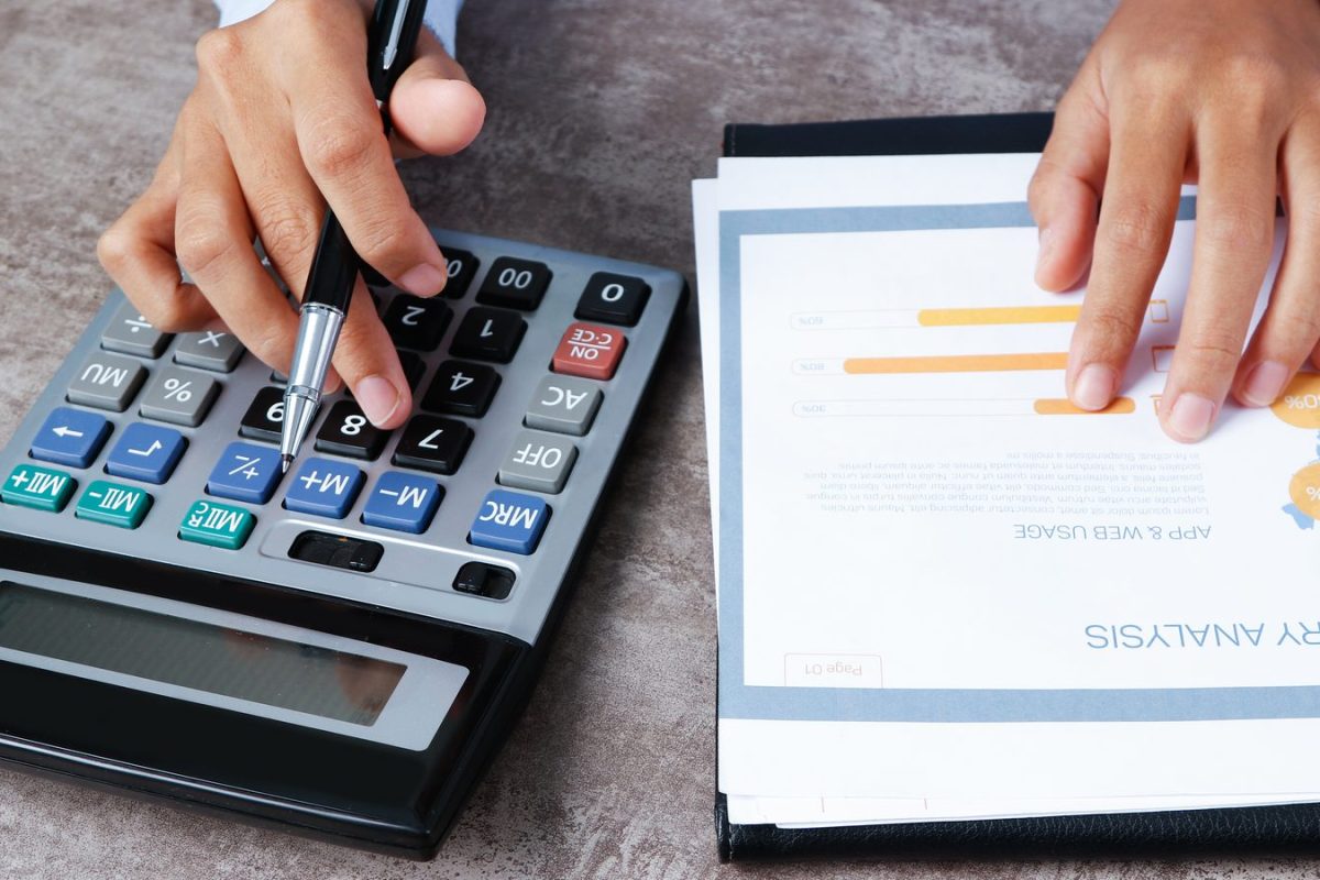 Calcul sur une calculatrice à côté d’un rapport chiffré, illustration du coût d’une comptabilité externalisée par pièce