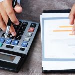 Calcul sur une calculatrice à côté d’un rapport chiffré, illustration du coût d’une comptabilité externalisée par pièce