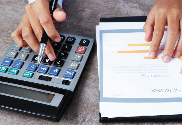Calcul sur une calculatrice à côté d’un rapport chiffré, illustration du coût d’une comptabilité externalisée par pièce