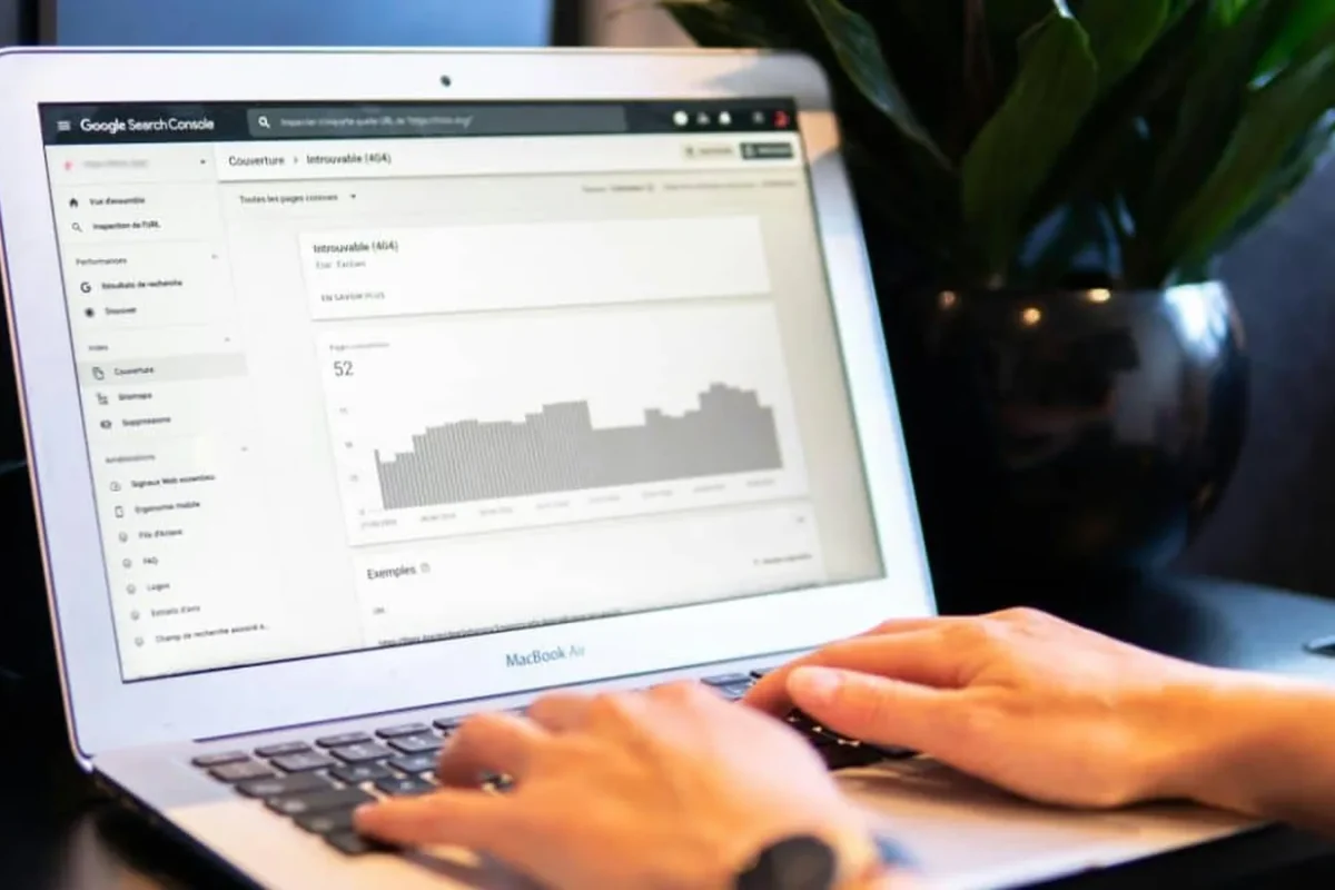 Mains sur le clavier d’un ordinateur portable affichant un rapport de couverture de la Search Console, illustration des délais d’indexation Google