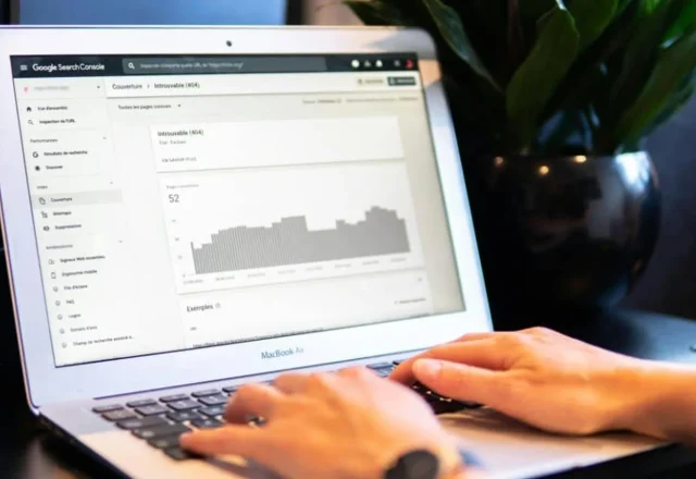 Mains sur le clavier d’un ordinateur portable affichant un rapport de couverture de la Search Console, illustration des délais d’indexation Google