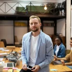 Responsable debout devant une table de réunion où travaille son équipe, un marqueur à la main