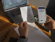Mains tenant un ticket de caisse et un smartphone affichant une application de virement
