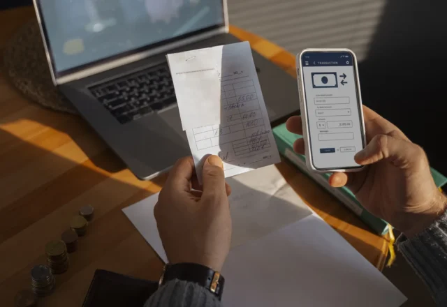 Mains tenant un ticket de caisse et un smartphone affichant une application de virement
