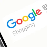 Logo Google Shopping affiché sur l'écran d'un smartphone posé sur un ordinateur portable