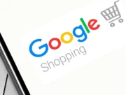 Logo Google Shopping affiché sur l'écran d'un smartphone posé sur un ordinateur portable