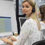 Conseillère équipée d'un casque dans un centre d'appels, devant un tableau de suivi à l'écran