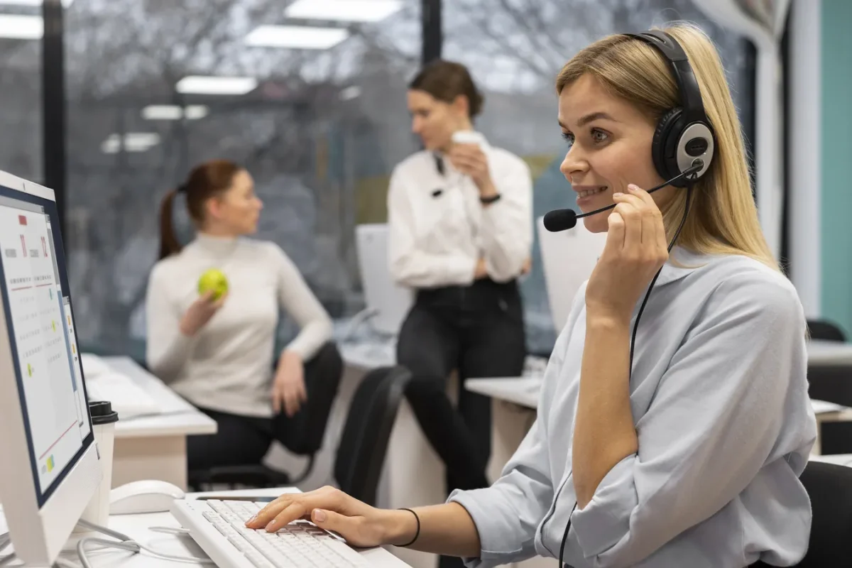 Conseillère en casque à son poste dans un centre de contacts, collègues en arrière-plan