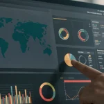 Doigt pointant un graphique sur un écran de tableau de bord avec carte du monde et indicateurs