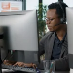 Conseiller équipé d'un casque travaillant sur ordinateur dans un centre de contacts