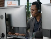 Conseiller équipé d'un casque travaillant sur ordinateur dans un centre de contacts