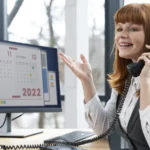 Femme au téléphone devant un écran affichant un calendrier de rendez-vous