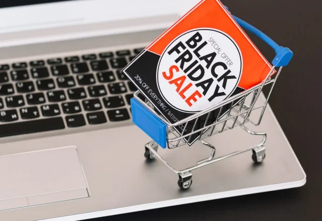 Mini chariot de supermarché contenant une affiche « Black Friday Sale », posé sur le clavier d’un ordinateur portable