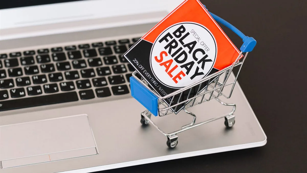 Mini chariot de supermarché contenant une affiche « Black Friday Sale », posé sur le clavier d’un ordinateur portable