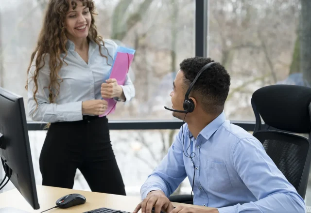 Conseiller en casque à son poste échangeant avec une collègue dans un centre de contacts externalisé