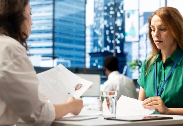 Entretien de recrutement : deux femmes examinent un CV et des documents à une table de bureau