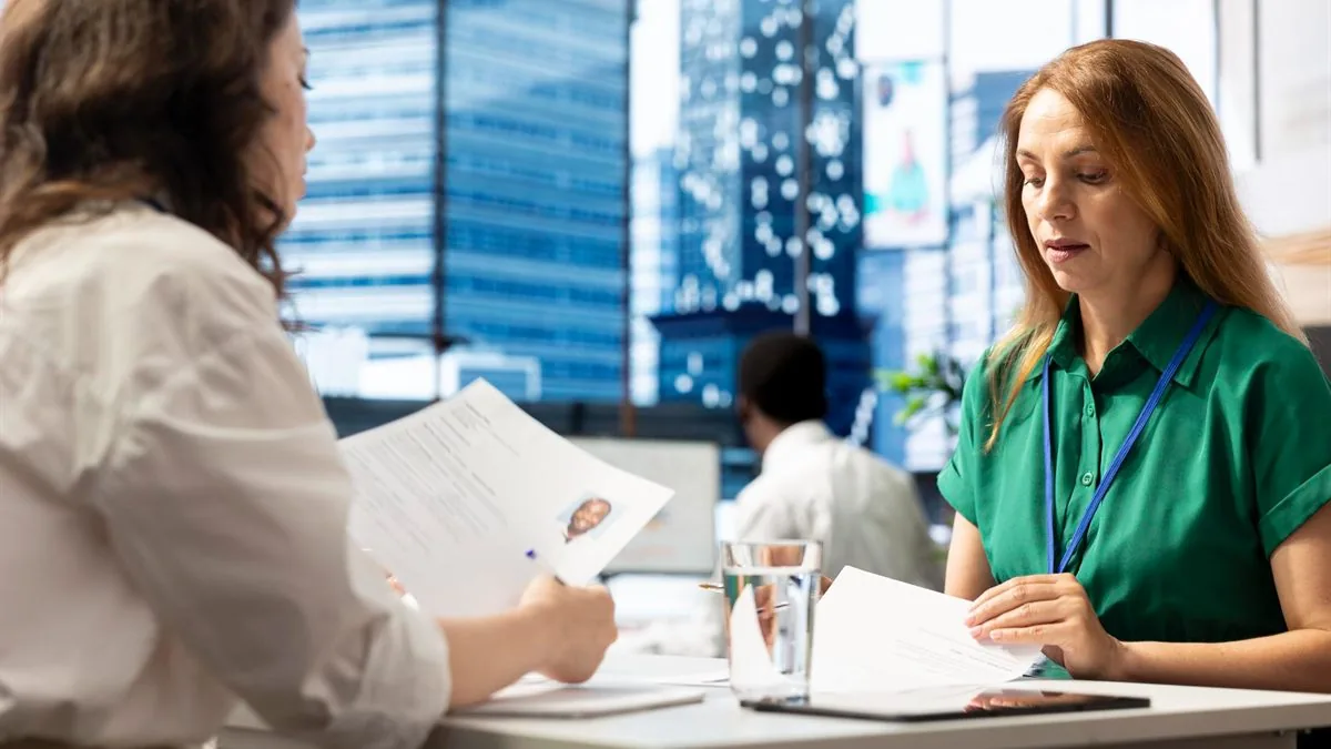 Entretien de recrutement : deux femmes examinent un CV et des documents à une table de bureau