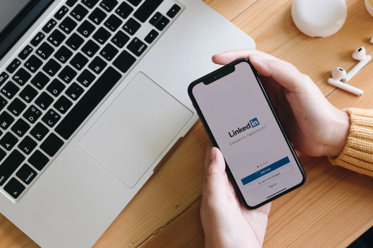 Smartphone affichant l'écran d'accueil de LinkedIn à côté d'un ordinateur portable
