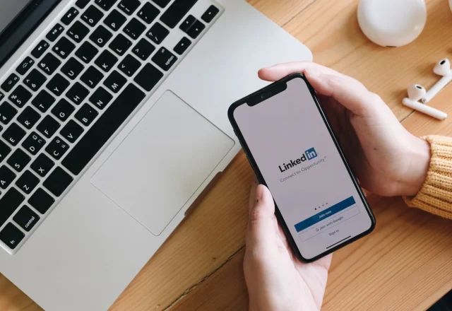 Smartphone affichant l'écran d'accueil de LinkedIn à côté d'un ordinateur portable